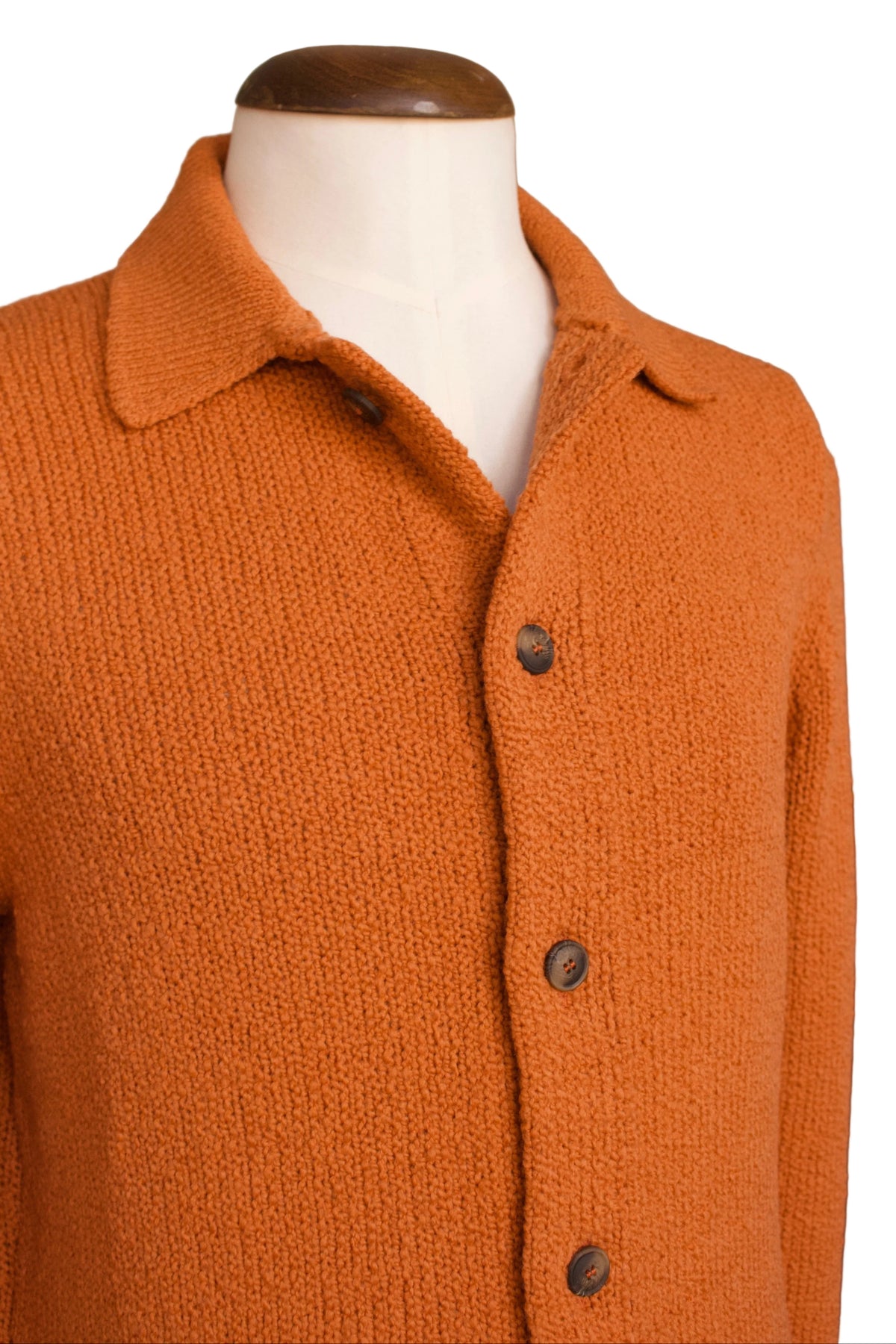 An orange knit cardigan sweater displayed on a white mannequin torso with a wooden neck cap, set against a white background.