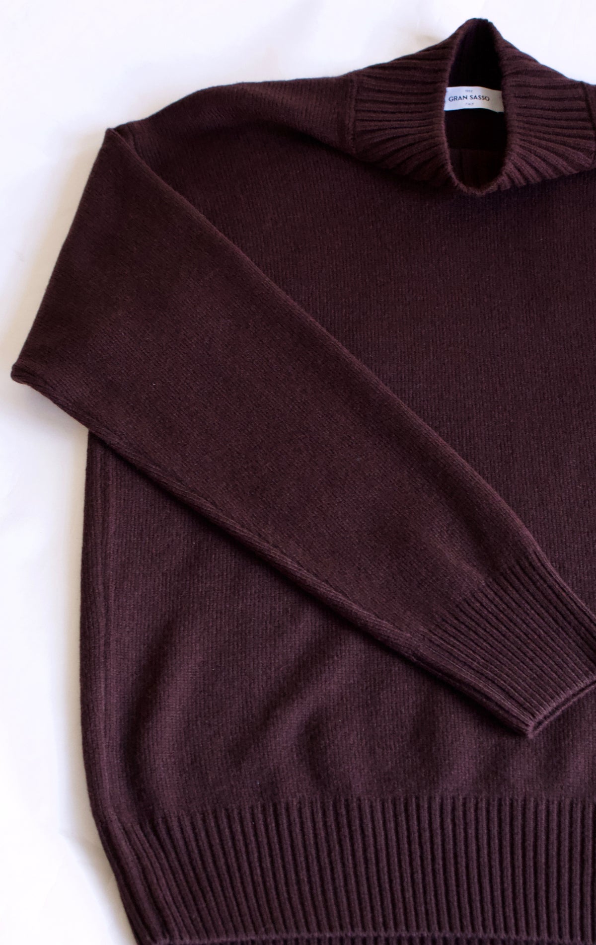 A dark brown knit sweater with a mock neck, laid flat on a white background.