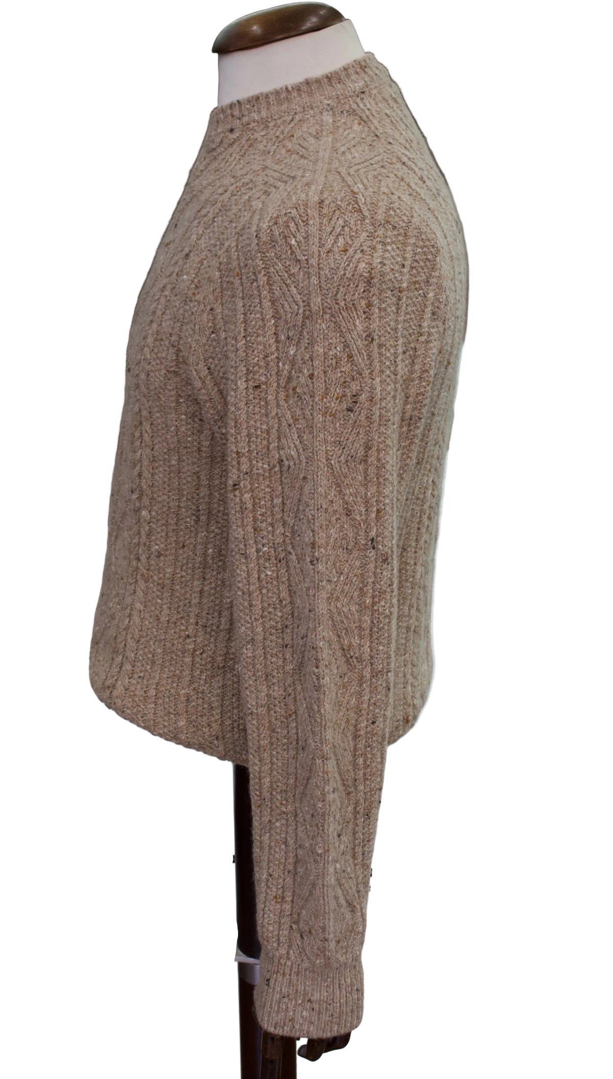 A beige Inis meain cable knit sweater displayed on a mannequin torso against a plain white background. The cable pattern has been tailored to be seen trailing down the arms from this side view.
