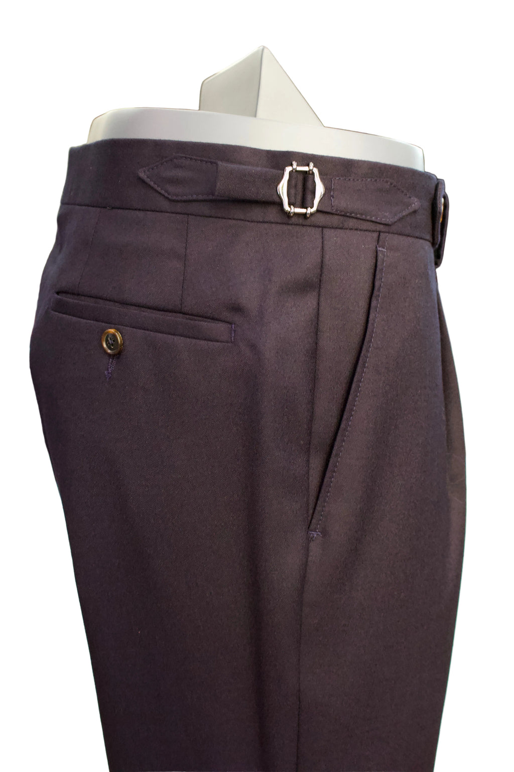 Dark navy tailored single pleat trousers displayed on a mannequin torso, featuring side adjusters with a silver buckle and a welt pocket with a decorative horn  button.